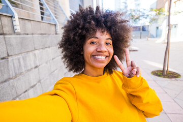 beautiful afro girl taking a picture with her phone to post it on he social media. Internet and...