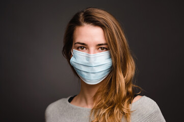 Beautiful young blonde woman with medical face mask during pandemic times of covid-19 in quarantine 