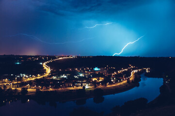 Fototapeta na wymiar A flash of lightning over the river in the night city