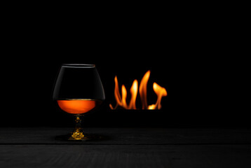 a glass of whisky with fireplace on background