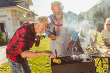 Elderly neighbors grilling meat at the backyard