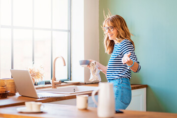 Woman using her laptop in the kitchen at home