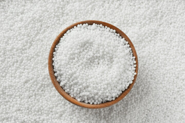 Bowl on pellets of ammonium nitrate, top view. Mineral fertilizer