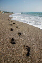 footprints on the beach. Footprints in the sand.  Sideways waves of calm sea