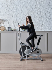 Training sportive woman at home, doing sport interior concept, decorative background and ride a bike style.