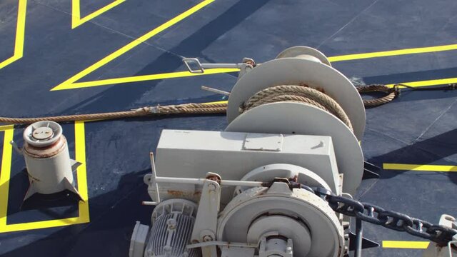 Large thick mooring rope being winched across the deck of a boat ship