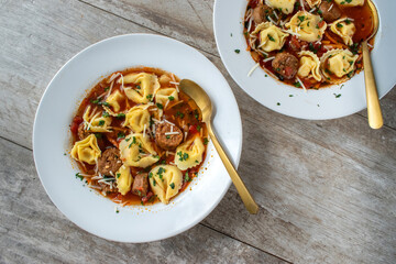 bowl of tortellini soup with Italian sausage flat lay
