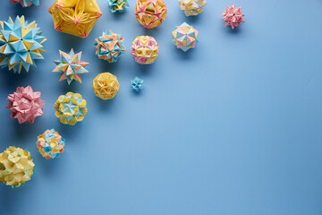 Set of multicolor handmade modular origami balls or Kusudama Isolated on blue background. Visual art, geometry, art of paper folding, paper crafts. Top view, close up, selective focus, copy space.