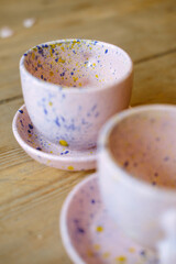 Ceramic cups on a pink saucer on a wooden table