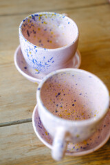 Ceramic cups on a pink saucer on a wooden table