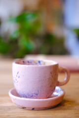Ceramic cups on a pink saucer on a wooden table