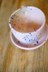 Ceramic cups on a pink saucer on a wooden table