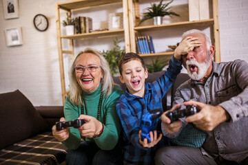 Happy grandparents playing video games with their grandson