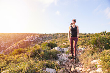 Obraz premium Fit woman walking on the mountain near the sea at sunrise . Healthy lifestyle concept