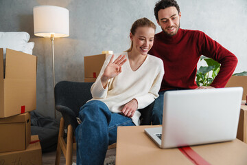 Smiling couple with laptop sitting on floor