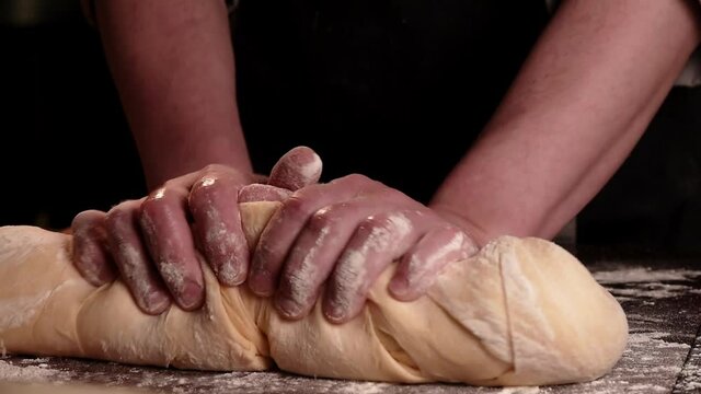 Baker chef  kneading floured dough for bread in homemade bakery.  Dark atmosphere. Close up