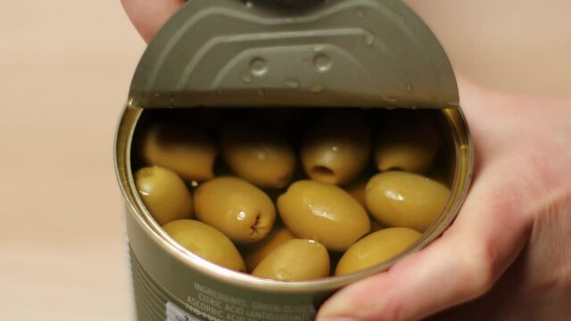 Close up person hand opening olive tin can and taking out olives.