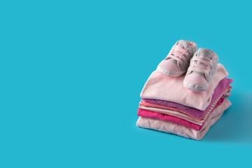 Baby rompers and baby shoes on blue background.Copy space