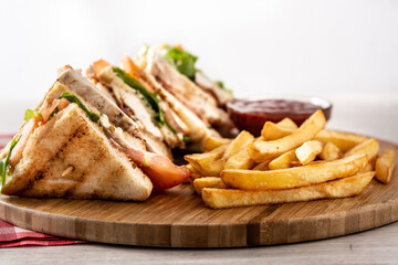 Club sandwich and French fries with ketchup sauce on wooden table	