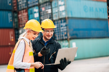 workers teamwork man and woman in safety jumpsuit workwear with yellow hardhat and use laptop check container at cargo shipping warehouse. transportation import,export logistic industrial service