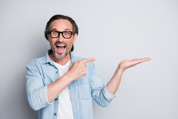 Photo of astonished handsome man open mouth finger direct empty space arm palm hold isolated on...