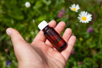 A small bottle with a natural extract in your hand. Medicinal preparation based on herbs - concept.