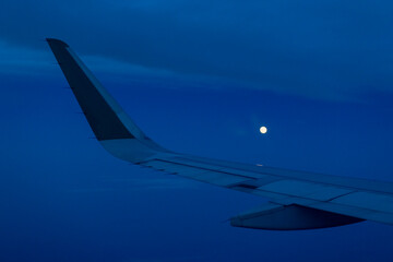 Wing of airplane in flight at Night With Moon
