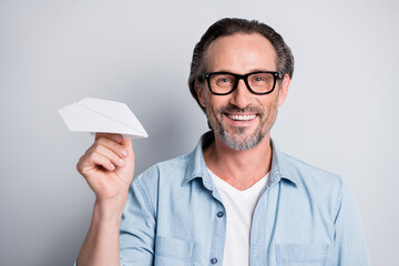 Photo of excited aged man happy positive smile hold paper plane origami isolated over grey color background