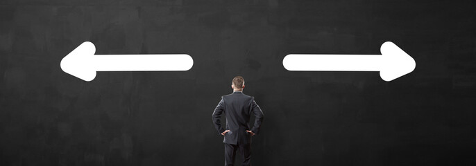 Young businessman looking at an empty space for text over black wall