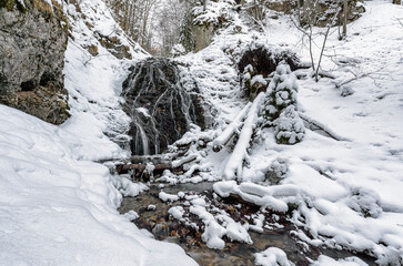 Fototapeta na wymiar Snowy waterfall called Nizny Jamisny vodpad in winter forest, Slovakia