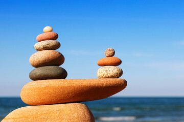 Two Rock zen pyramids of colorful pebbles on a beach on the background of the sea.