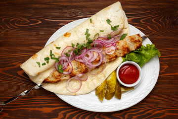 Chicken barbecue on a white plate on a dark wooden table