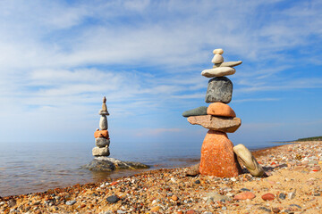 Two Rock zen pyramids of colorful pebbles on a beach on the background of the sea.