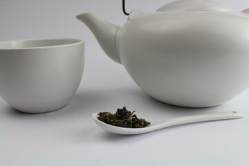 grüner Tee mit weißer asiatischer Teekanne im Hintergrund 
