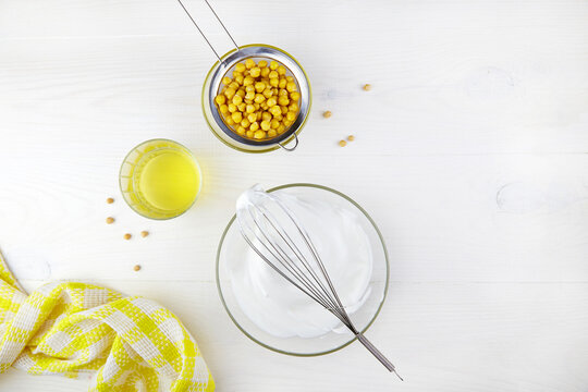 Aquafaba and whipped liquid from boiled chickpeas in glass bowl with whisk. Replace egg in baking for vegan recipe.