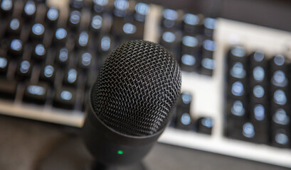 Microphone, mike condenser black metallic, blur keypad background.