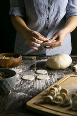 Woman preparing dumplings dark background 