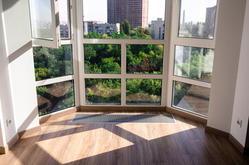 Panoramic window. Underfloor heater grill. Sharp shadows from the panoramic window frame on the wooden floor