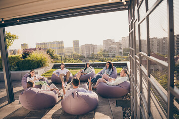 Photo of group chief leaders sitting bean bags discuss new stratagy workplace workstation outdoors outside city terrace
