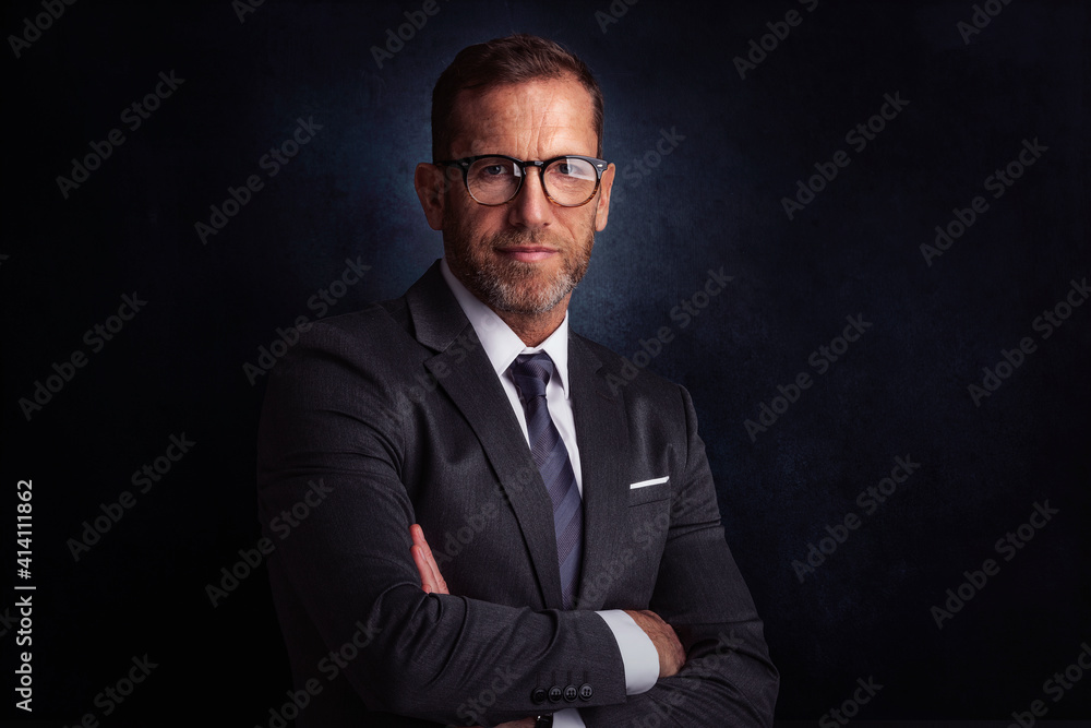 Wall mural Portrait of senior businessman standing at isolated dark background