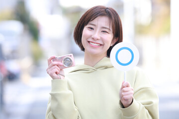 コンパクトデジタルカメラと〇札を持つ女性