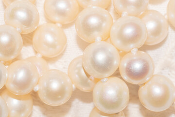 close up of white pearl necklace on an ivory fabric