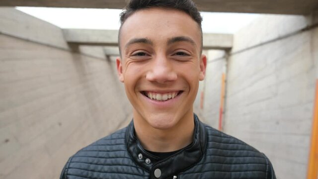 Close up of one young man smiling and laughing looking at the camera having fun. Portrait of teenager opening eyes feeling good.
