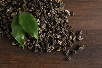 Heap of dried green tea leaves on wooden table, closeup