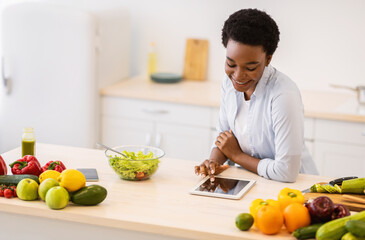 Black Woman Using Tablet Cooking Browsing Recipes Online In Kitchen