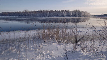 Fototapeta na wymiar Winter landscape: the Burnaya river flows into Lake Ladoga, trees covered with hoarfrost, panoramic view