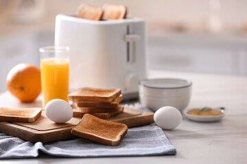 Modern toaster and delicious breakfast on table in kitchen