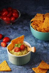 Homemade guacamole with corn chips and cherry tomatoes