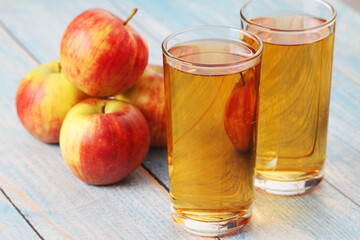 A glass with apple juice and ripe apples
