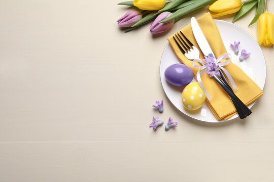 Festive Easter table setting with eggs on beige background, flat lay. Space for text